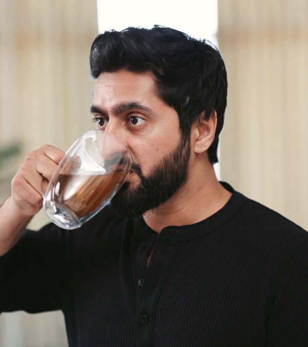 Man drinking shilajit tea from a glass mug